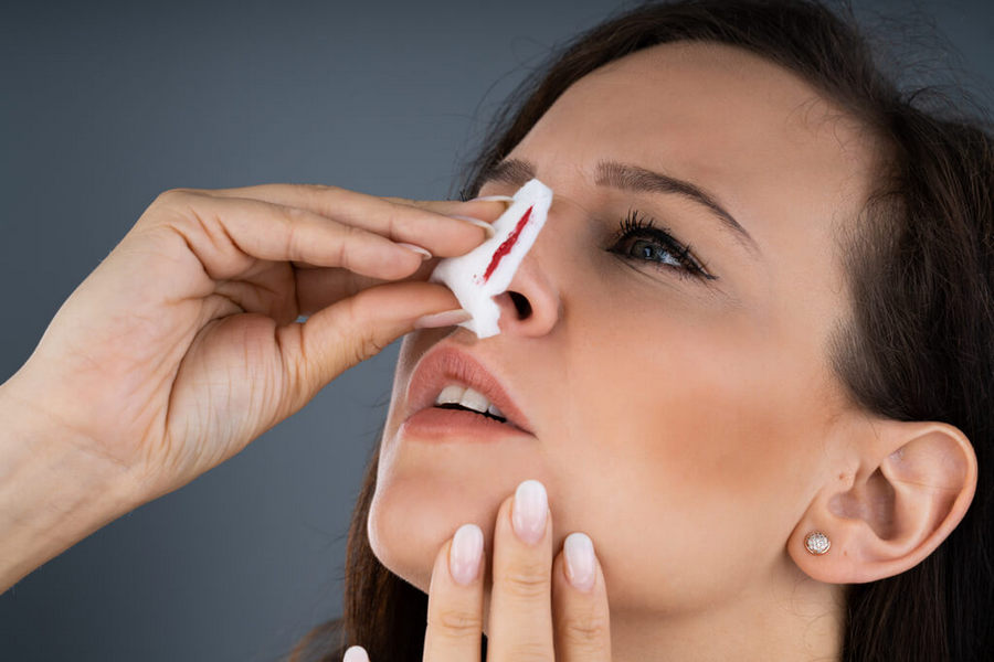 Woman trying to stop blood bleeding from nose
